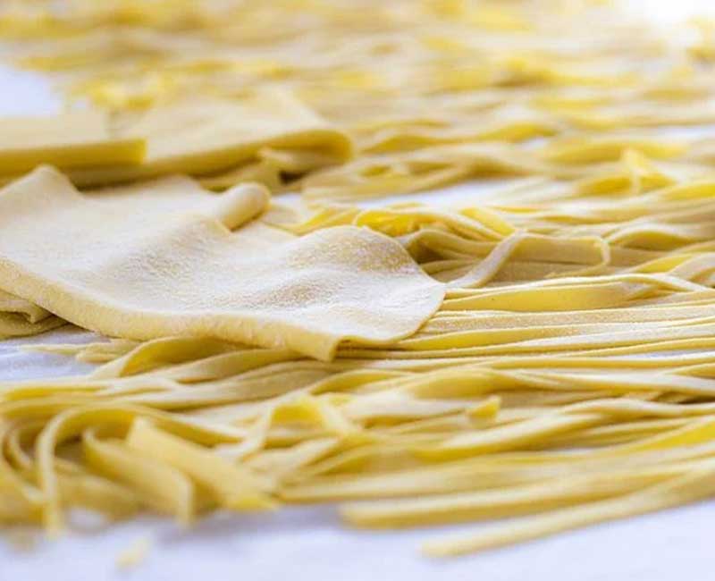 Pâtes farinées et rouleau à pâtisserie sur un plan de travail