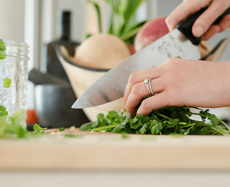 Mains hachant des herbes vertes sur une planche
