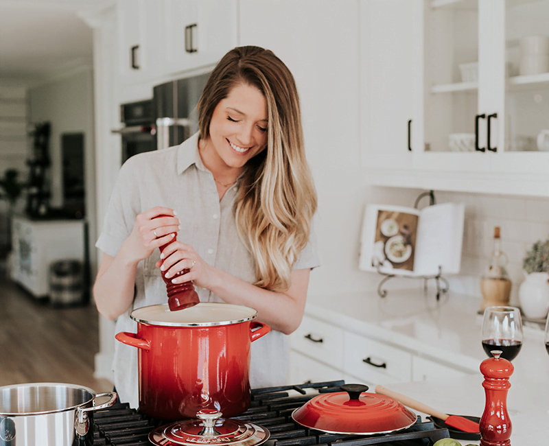 Personne cuisinant devant une casserole rouge