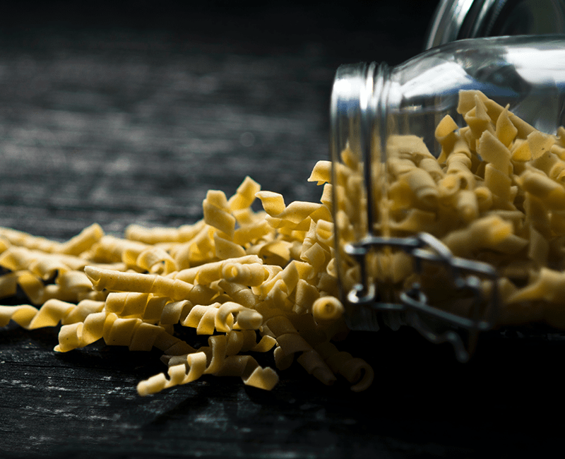 Fusilli secs sur une fourchette, devant un fond sombre