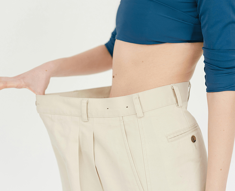 Personne tenant la ceinture d’un pantalon devenu trop large