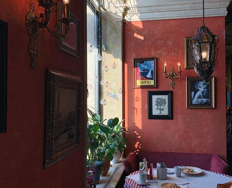 Salle de restaurant aux murs rouges et aux tables dressées