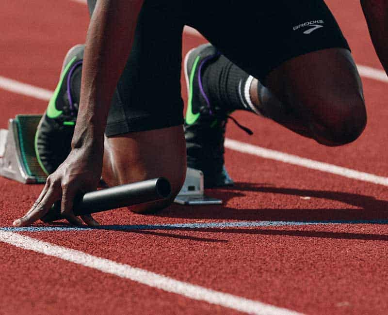 Athlète sur une piste, les pieds placés dans des starting-blocks