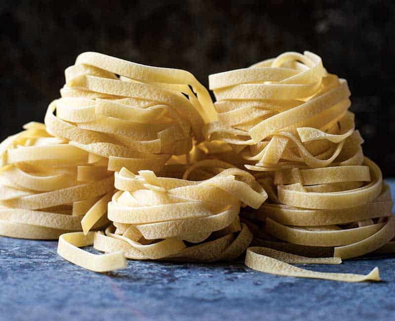 Nids de pâtes sur une surface sombre saupoudrée de farine