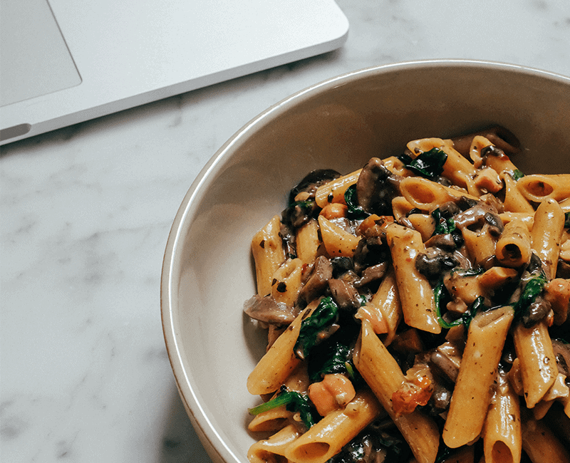 Penne servies avec des légumes et des feuilles vertes