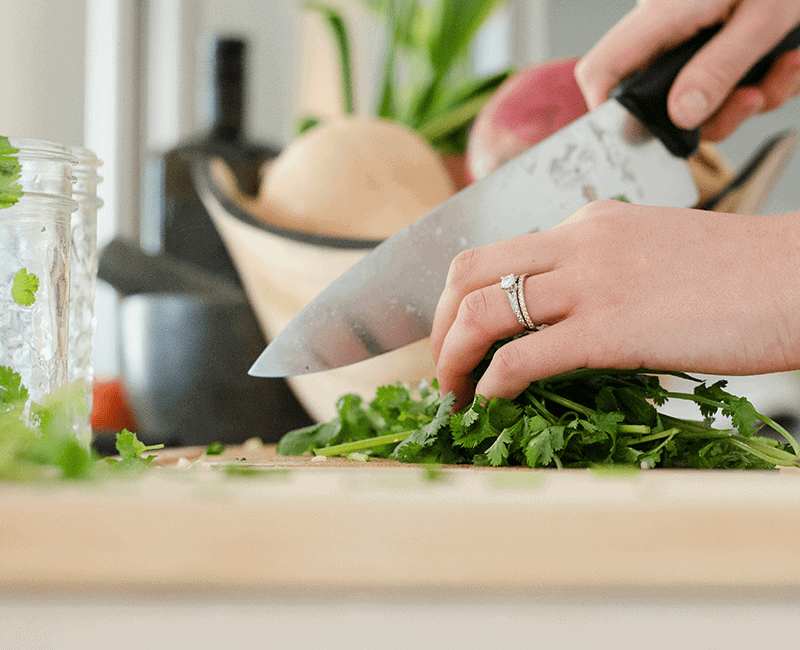 Mains hachant des herbes vertes sur une planche