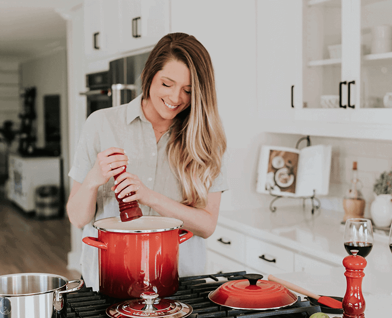 Personne cuisinant devant une casserole rouge