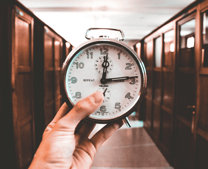 Main tenant une horloge devant un fond clair