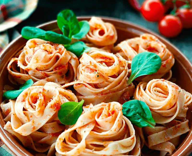 Nids de pâtes avec tomates et basilic sur un plan de travail