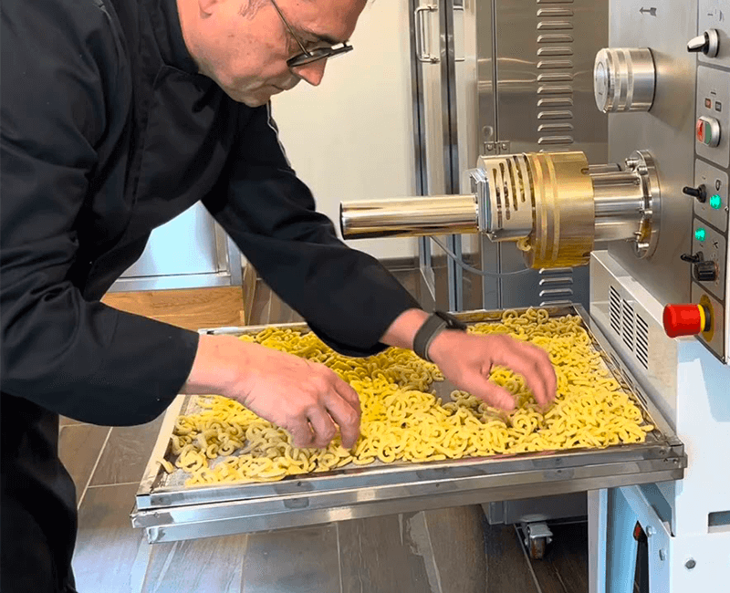Personne travaillant devant une machine de fabrication de pâtes