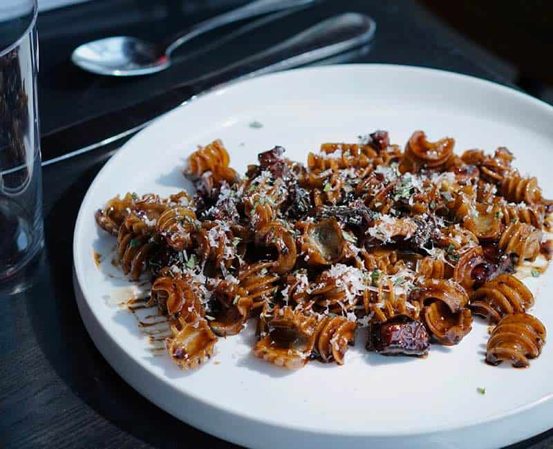 Radiatori servis avec une sauce sombre et des morceaux de garniture