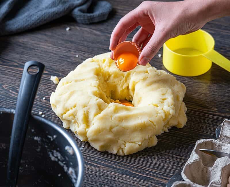 Préparation de pommes de terre écrasées avec farine et œuf sur un plan de travail