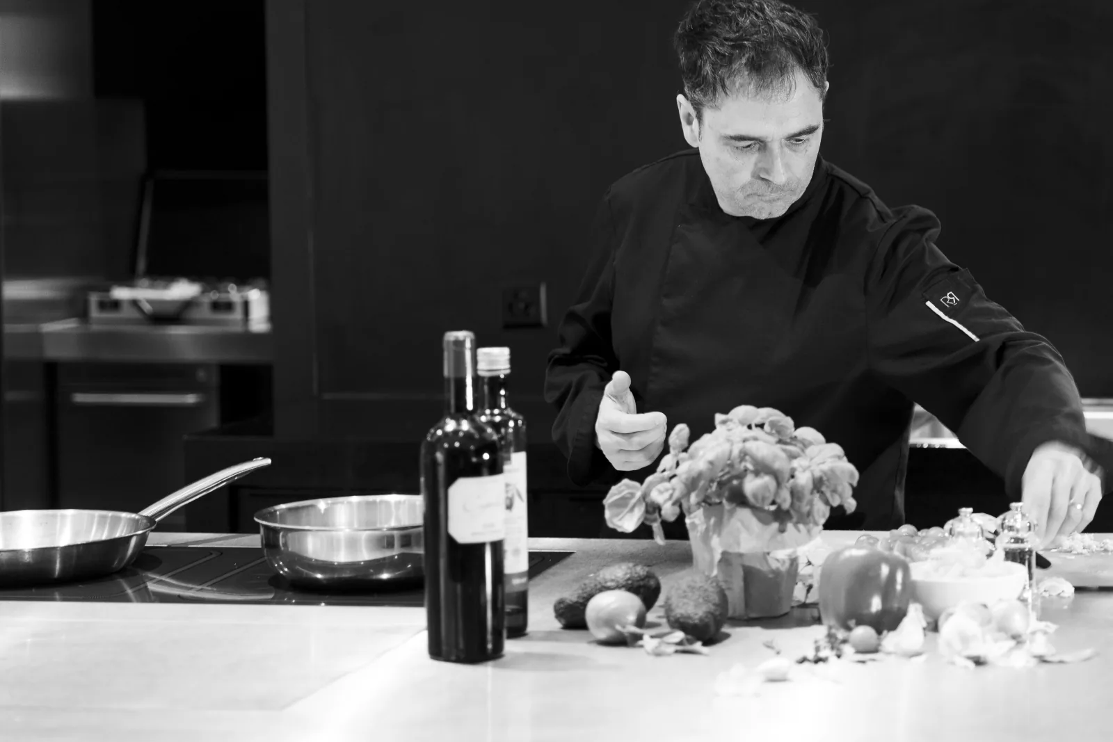 Bertrand Larzul préparant des légumes en cuisine, photographie en noir et blanc.